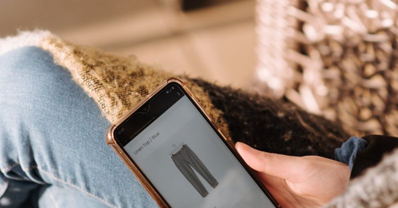 Mobile Ecommerce - High angle of unrecognizable woman sitting on chair and choosing clothes in internet shop using mobile phone