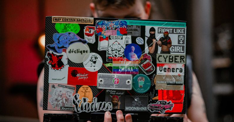 Remarketing Ppc - A man holding a laptop with a bunch of stickers on it