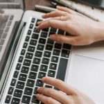 Keyword Search - From above of unrecognizable woman sitting at table and typing on keyboard of computer during remote work in modern workspace