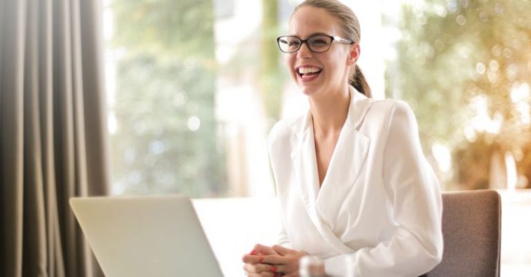 Employee Advocacy - Laughing businesswoman working in office with laptop